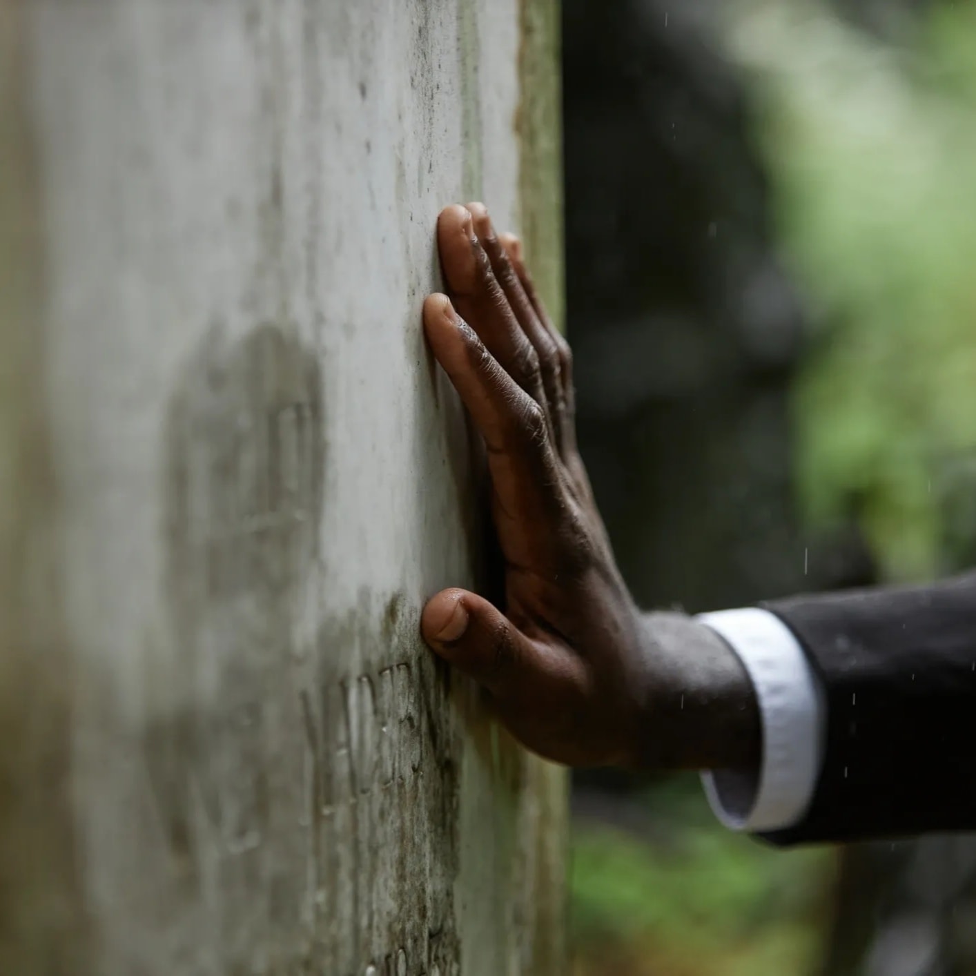 Hands resting on a memorial gravestone in remembrance